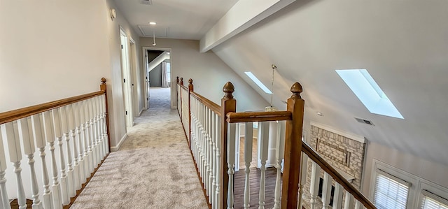 hallway featuring lofted ceiling with skylight and light carpet