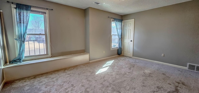 carpeted empty room with a textured ceiling