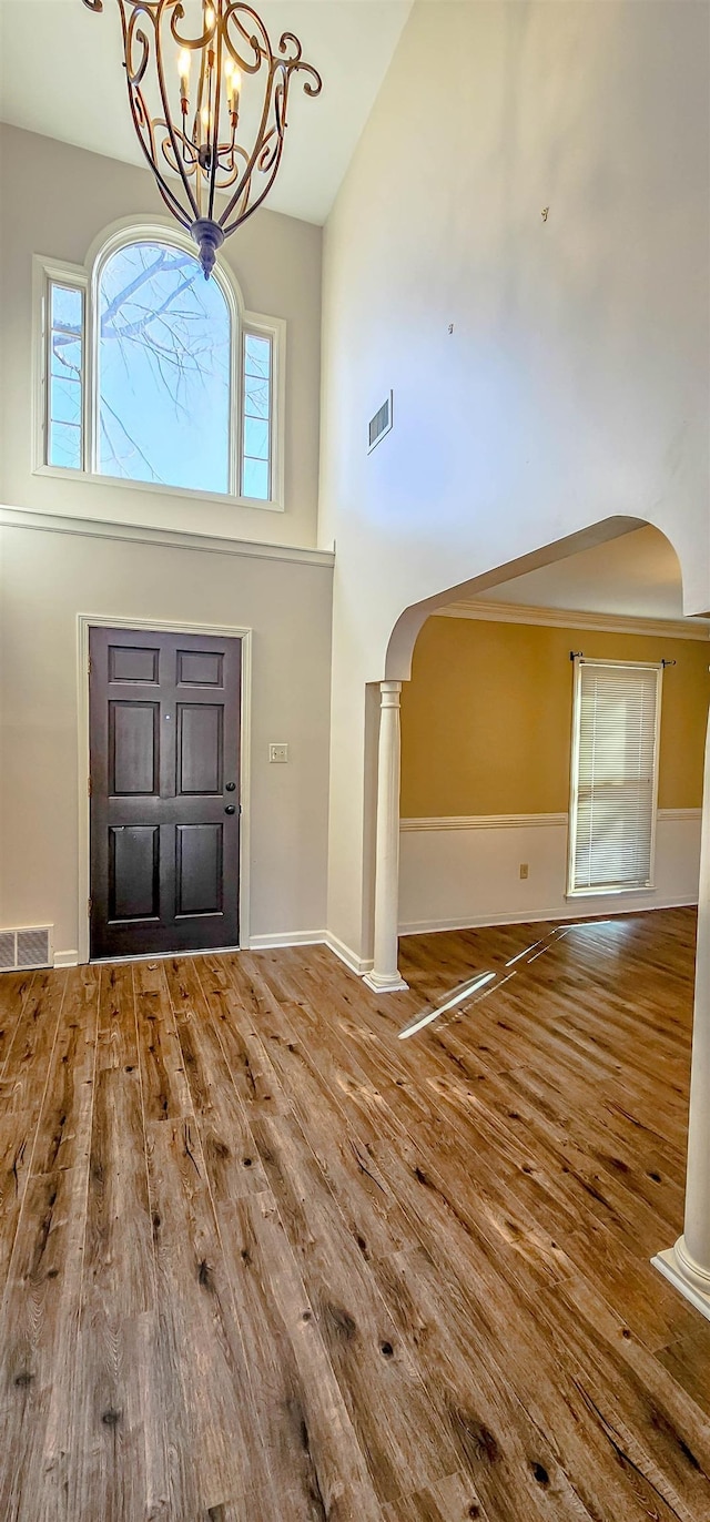 foyer with an inviting chandelier, hardwood / wood-style floors, a high ceiling, and ornate columns