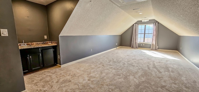 bonus room with light colored carpet, bar, vaulted ceiling, and a textured ceiling