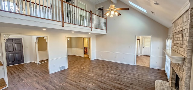 unfurnished living room featuring ceiling fan, dark hardwood / wood-style floors, a skylight, and high vaulted ceiling