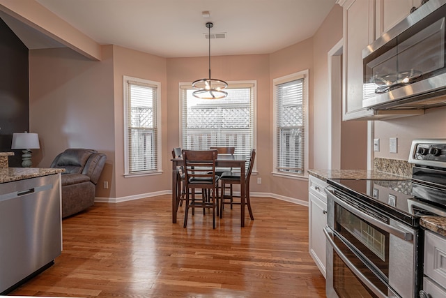 dining room with a notable chandelier, a wealth of natural light, and light wood-type flooring