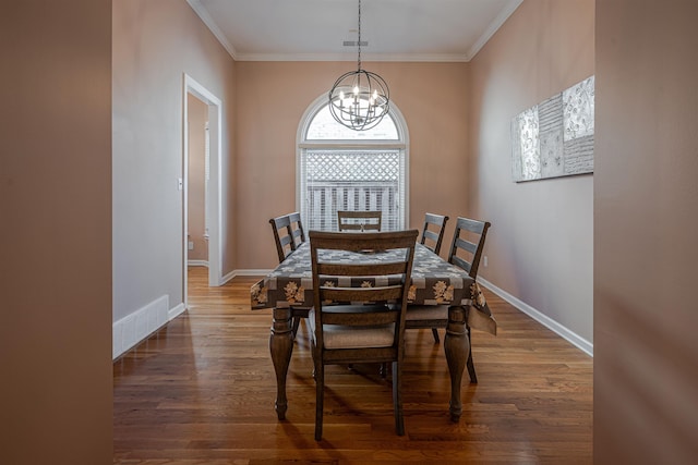 dining area with crown molding, dark wood-type flooring, and a chandelier