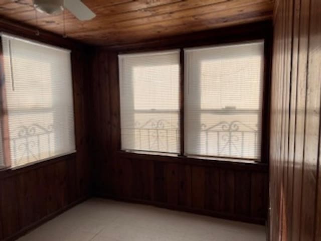 empty room featuring ceiling fan, wooden walls, and wood ceiling