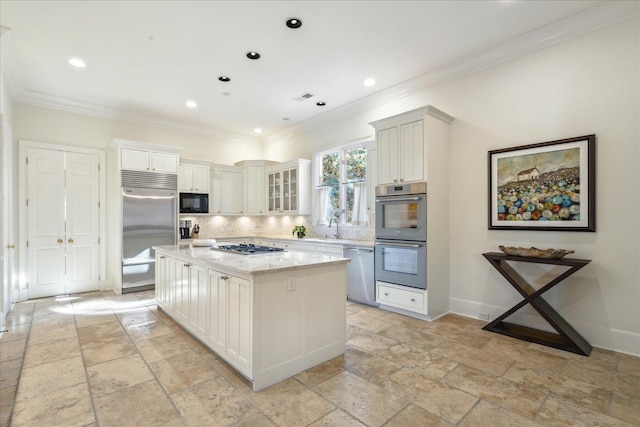 kitchen featuring built in appliances, sink, a kitchen island, and white cabinets