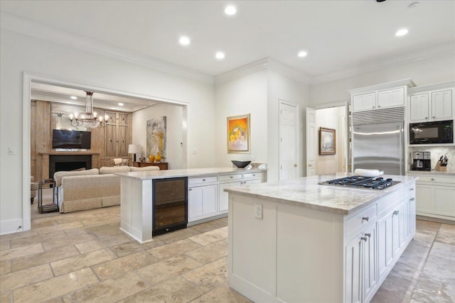 kitchen with white cabinets, beverage cooler, ornamental molding, a center island, and built in appliances