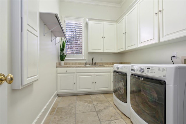 laundry room featuring sink, crown molding, washer and clothes dryer, and cabinets