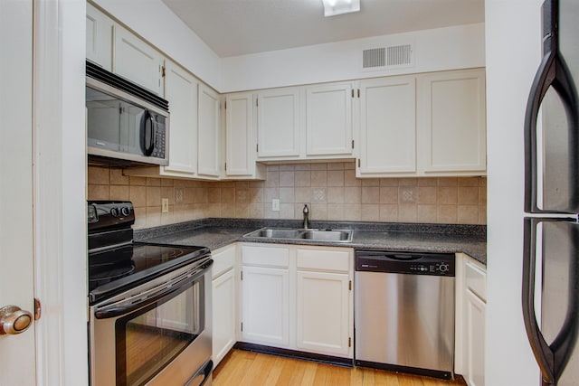 kitchen featuring sink, light hardwood / wood-style flooring, white cabinetry, stainless steel appliances, and tasteful backsplash