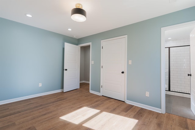 unfurnished bedroom with ensuite bathroom and light hardwood / wood-style flooring