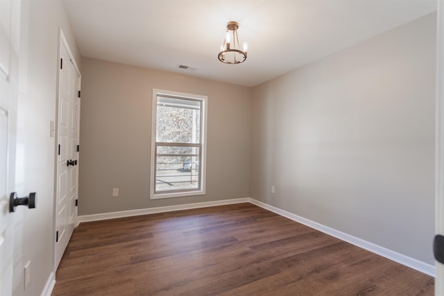 spare room featuring a chandelier and dark hardwood / wood-style flooring