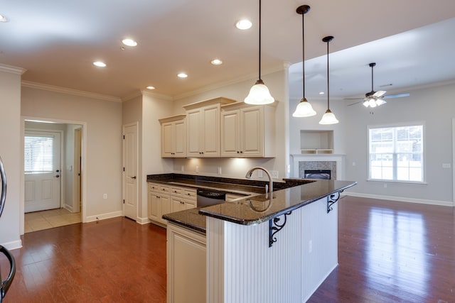 kitchen with dishwasher, sink, a kitchen breakfast bar, dark stone counters, and hanging light fixtures