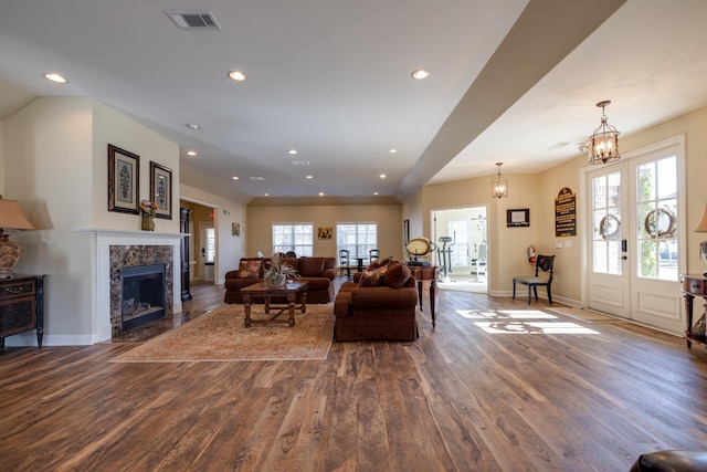 living room featuring an inviting chandelier, wood-type flooring, a fireplace, and plenty of natural light