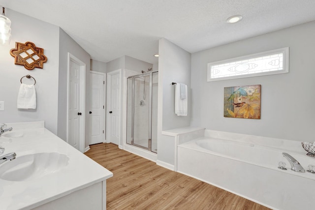 bathroom featuring vanity, wood-type flooring, a textured ceiling, and separate shower and tub