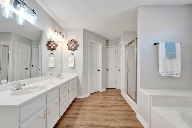 bathroom with vanity, plus walk in shower, wood-type flooring, and a textured ceiling