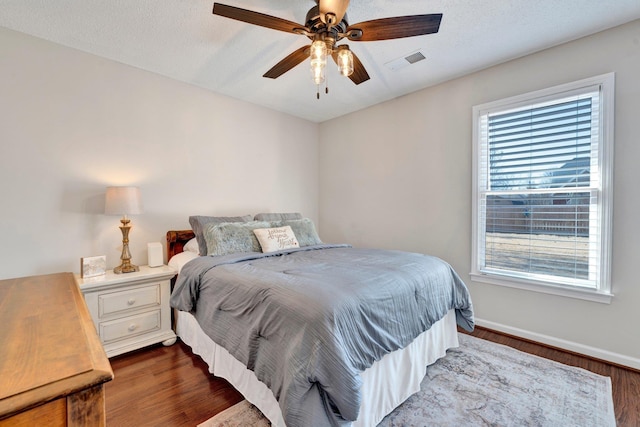 bedroom with a textured ceiling, dark wood-type flooring, and ceiling fan