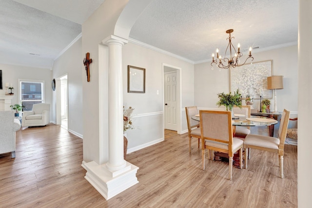 dining area featuring decorative columns, ornamental molding, a textured ceiling, a chandelier, and light wood-type flooring