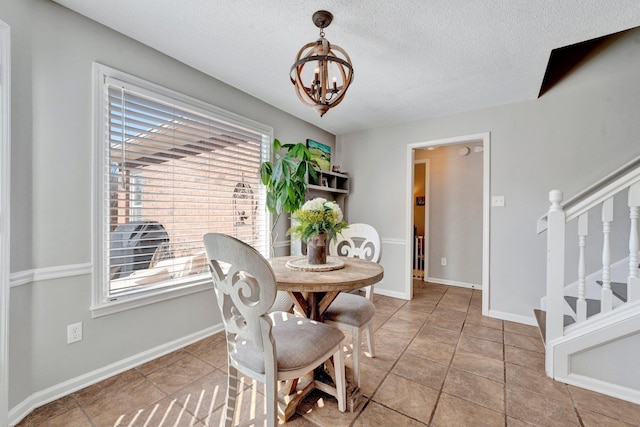 dining room with a textured ceiling, tile patterned floors, and an inviting chandelier