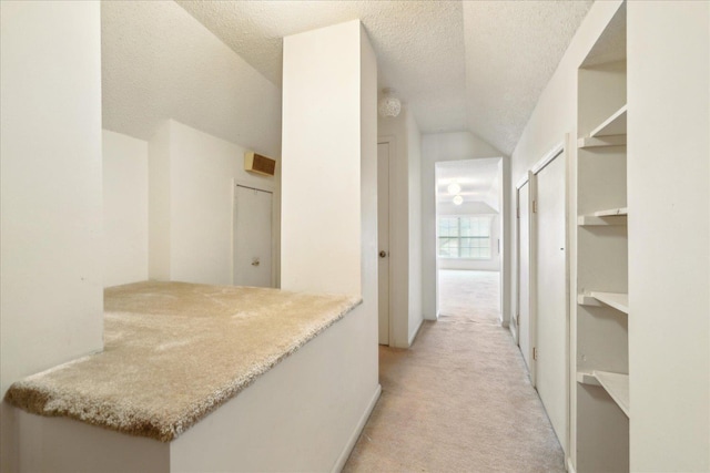 corridor featuring lofted ceiling, light carpet, and a textured ceiling