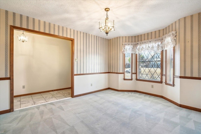 carpeted spare room featuring a notable chandelier and a textured ceiling