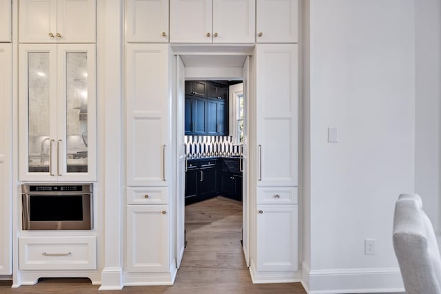 kitchen featuring white cabinets, light hardwood / wood-style flooring, and stainless steel oven