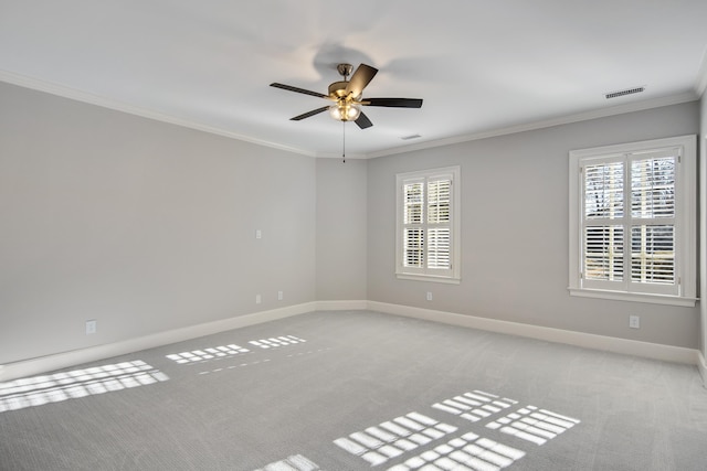 empty room with crown molding, a wealth of natural light, light colored carpet, and ceiling fan