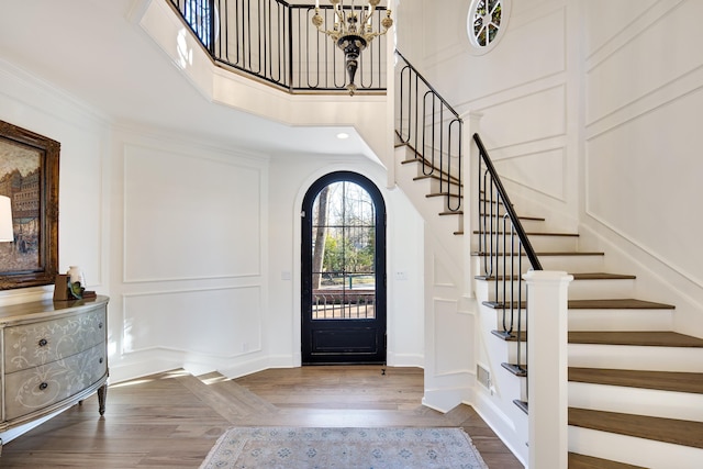 entryway featuring crown molding, hardwood / wood-style flooring, a chandelier, and a high ceiling