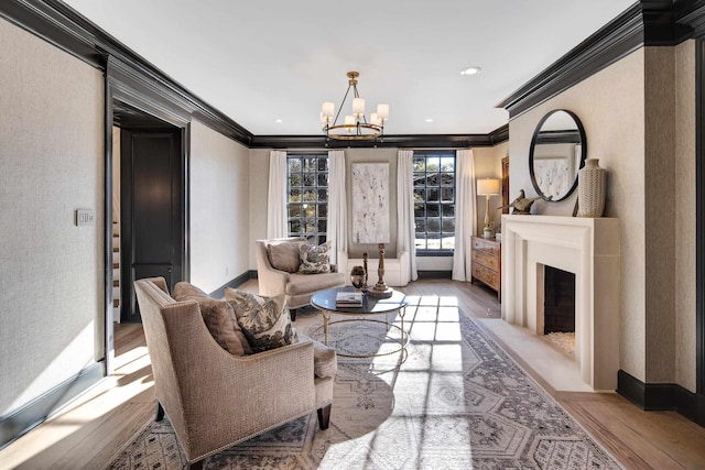 living room with ornamental molding, a chandelier, and light hardwood / wood-style flooring