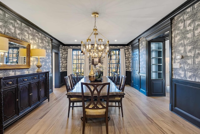 dining area featuring light hardwood / wood-style flooring, ornamental molding, and a chandelier