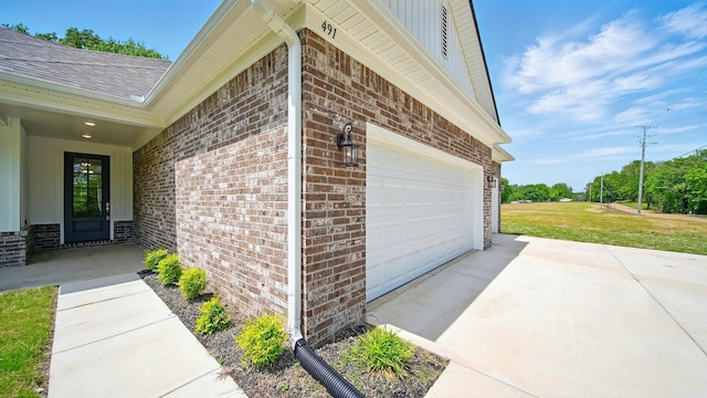 view of property exterior with a shingled roof, a yard, brick siding, concrete driveway, and an attached garage