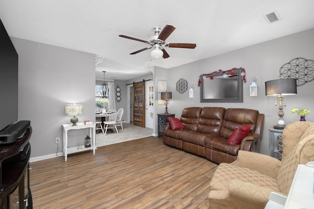 living room with hardwood / wood-style flooring, ceiling fan, and a barn door