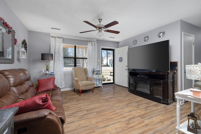 living room featuring ceiling fan, light hardwood / wood-style floors, and a textured ceiling