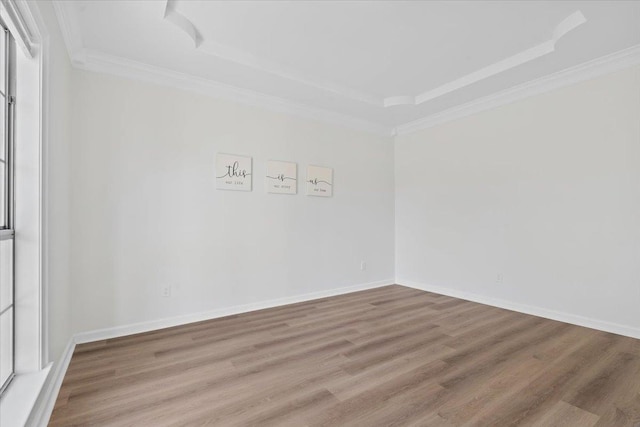 empty room featuring ornamental molding, wood-type flooring, and a tray ceiling