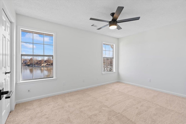 carpeted spare room with ceiling fan, a textured ceiling, and a water view