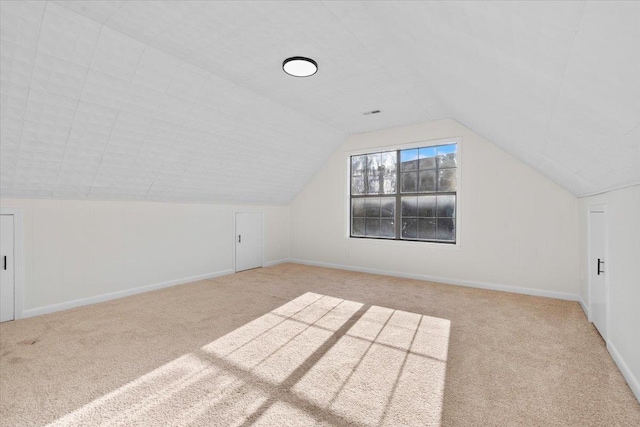 bonus room with lofted ceiling and light colored carpet