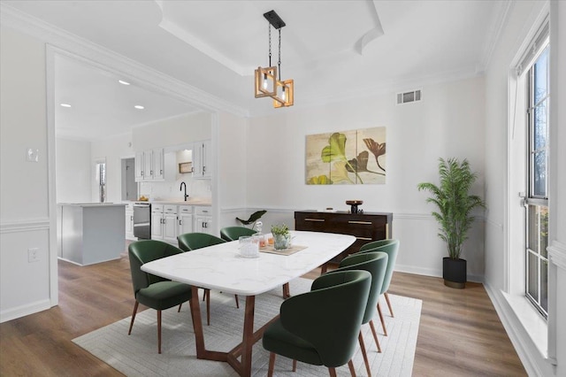 dining space featuring wood-type flooring, sink, and crown molding