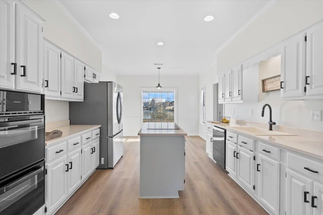 kitchen with decorative light fixtures, sink, white cabinets, a center island, and stainless steel appliances