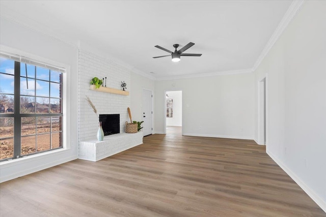 unfurnished living room featuring a brick fireplace, crown molding, a wealth of natural light, and hardwood / wood-style floors