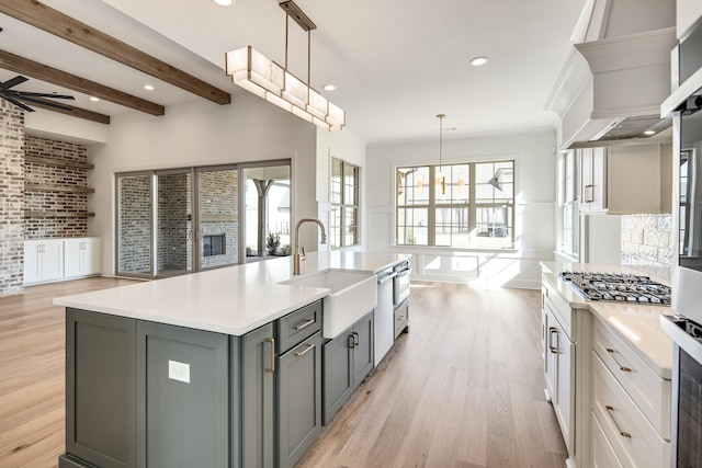 kitchen featuring gray cabinetry, open floor plan, light countertops, beamed ceiling, and stainless steel gas stovetop