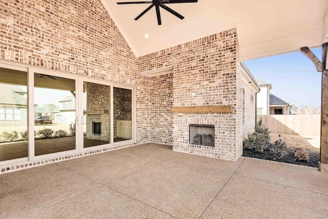 view of patio with an outdoor brick fireplace, fence, and a ceiling fan