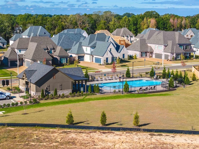 community pool featuring a yard, fence, and a residential view