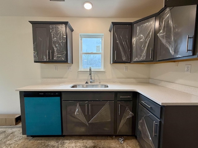 kitchen with light countertops, a sink, and dishwashing machine