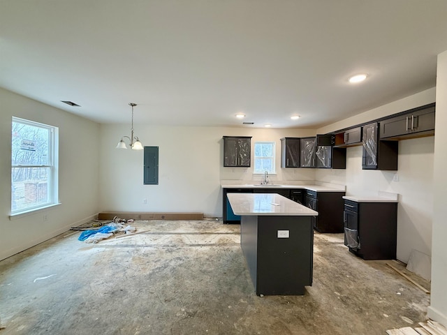 kitchen with a sink, light countertops, hanging light fixtures, electric panel, and a center island