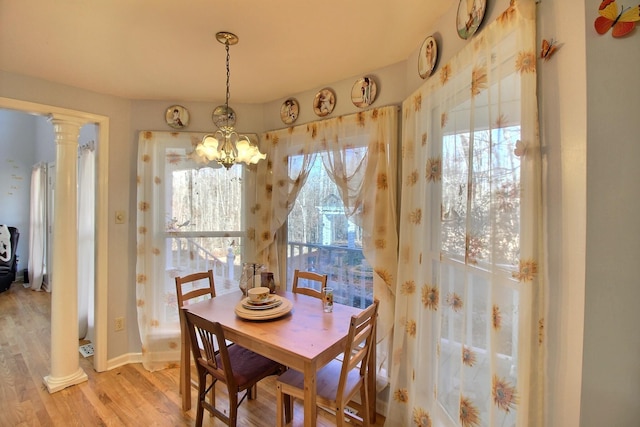 dining room featuring decorative columns, an inviting chandelier, and light wood-type flooring