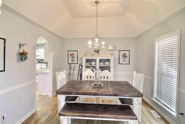 dining room with a raised ceiling, a notable chandelier, and light hardwood / wood-style floors