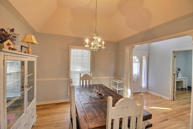 dining area featuring a notable chandelier, vaulted ceiling, decorative columns, and light wood-type flooring