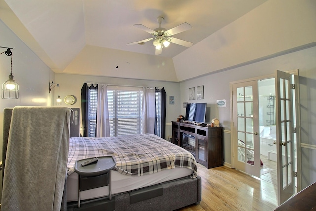 bedroom featuring ceiling fan, a tray ceiling, light hardwood / wood-style floors, vaulted ceiling, and french doors