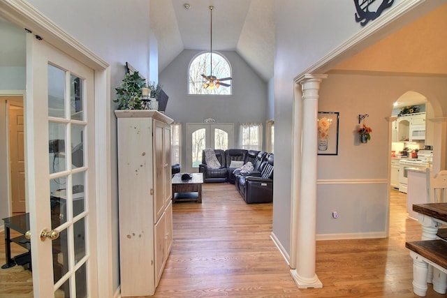 hallway featuring decorative columns, high vaulted ceiling, light hardwood / wood-style floors, and french doors