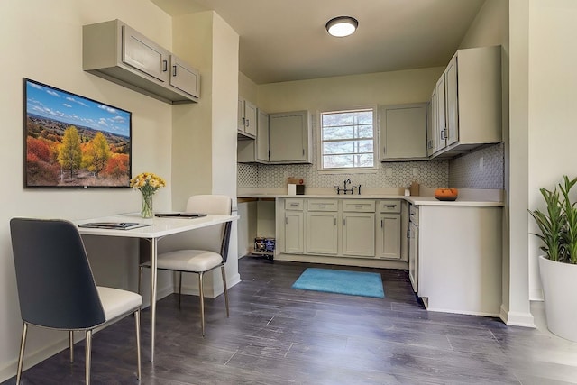 kitchen with sink, dark wood-type flooring, gray cabinetry, and decorative backsplash