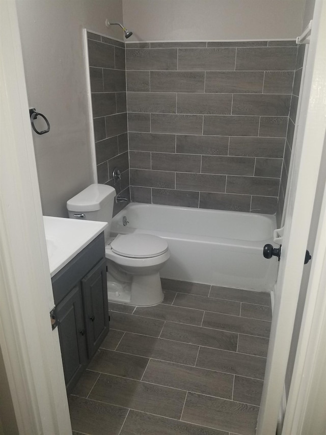 full bathroom with vanity, tiled shower / bath combo, and toilet