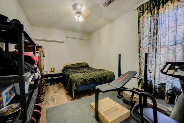 bedroom with hardwood / wood-style flooring, a textured ceiling, and ceiling fan